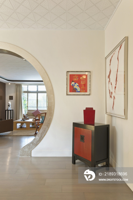 Side table against paintings on wall with living room in the background at modern house