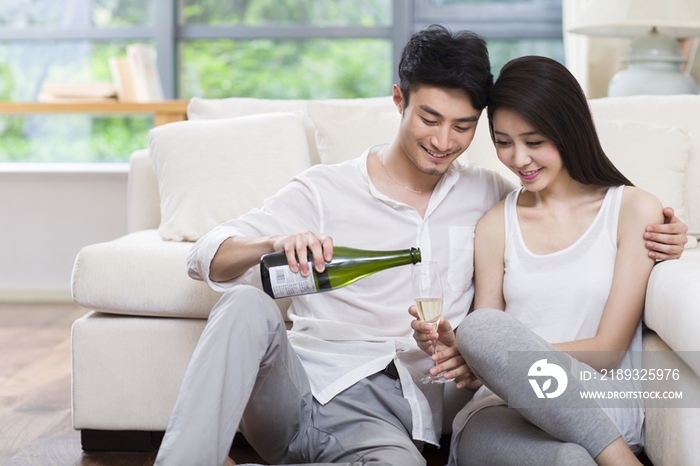 快乐的年轻情侣在客厅喝香槟