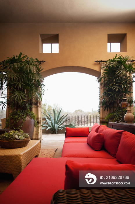 Contemporary living room with red furniture and view of plants through arched wall; Scottsdale; USA
