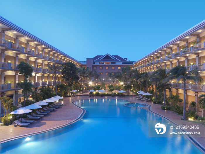 Illuminated hotel building with swimming pool at dusk