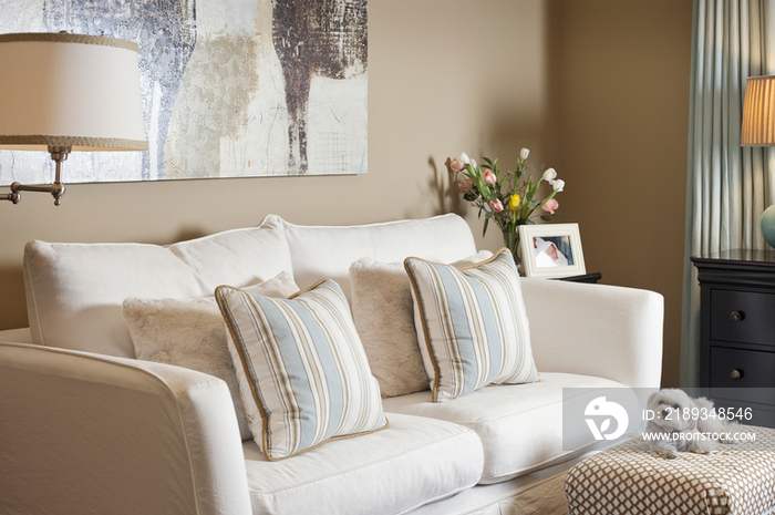 Sofa set with random objects on end table against window in living room at house