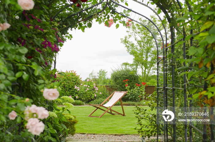 A country garden with a rose arch, and flowering climbing roses