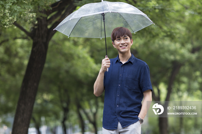 快乐的年轻男子打着雨伞
