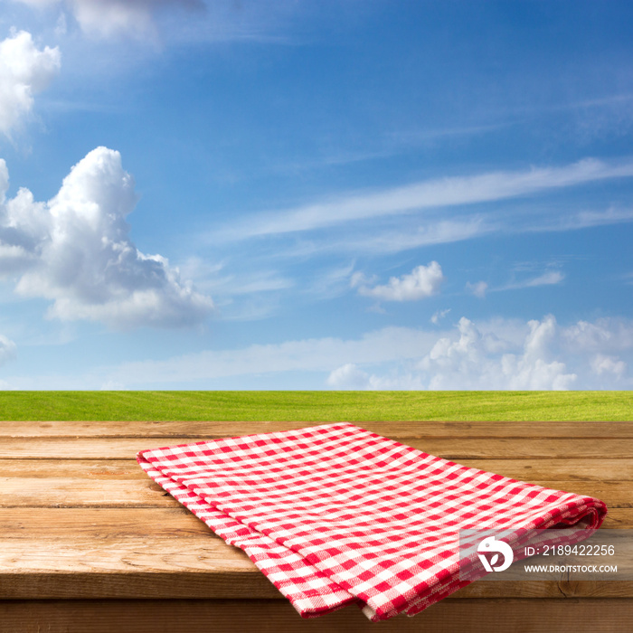 Empty table with tablecloth over beautiful meadow and blue sky