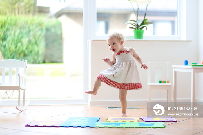 Happy blonde toddler girl having fun dancing indoors