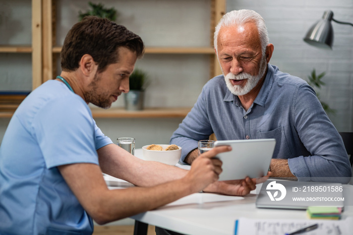 Happy mature man and his doctor using digital tablet during medical consultations.