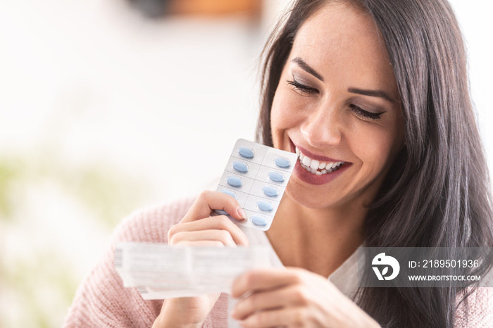 Woman reading a label of pills packaging, smiling