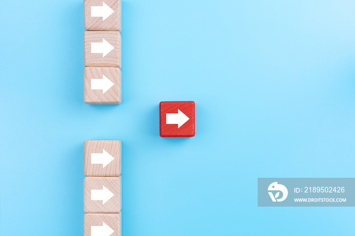 Leadership concept, Red wooden block with arrow icon on blue background.