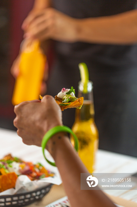 Restaurant visitors eating mexican snack nachos with guacamole sauce