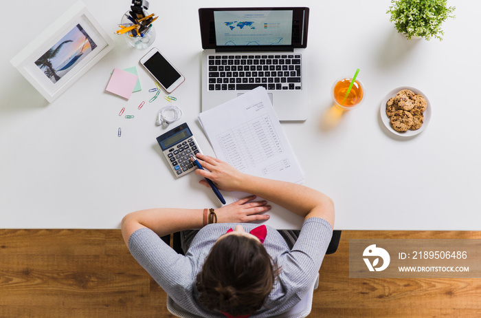 woman with calculator and papers at office table