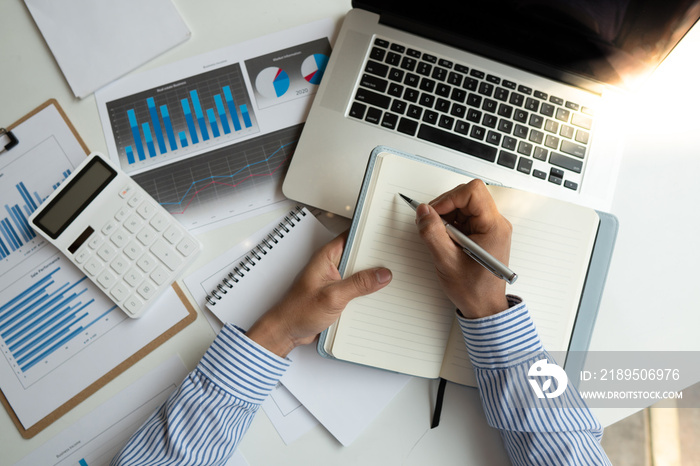 Top view. accountant is recording the companys financial growth. Using graphs as references and tak
