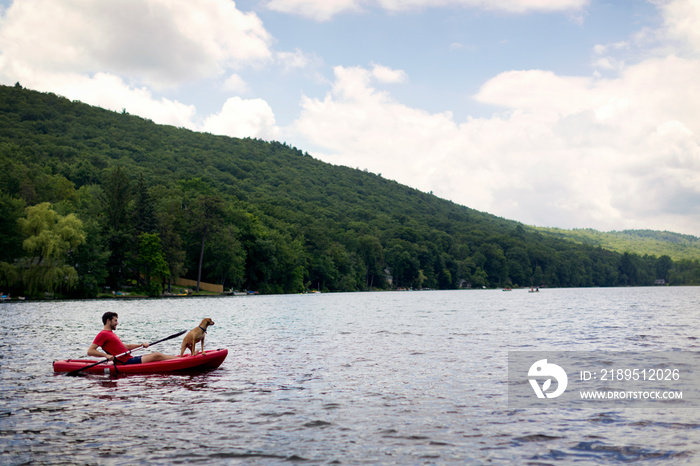 Man kayaking on lake with dog