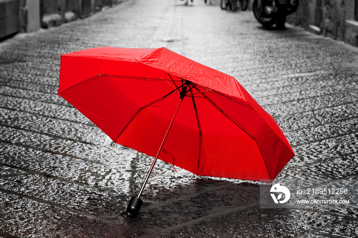 老城鹅卵石街道上的红色雨伞。风雨兼程