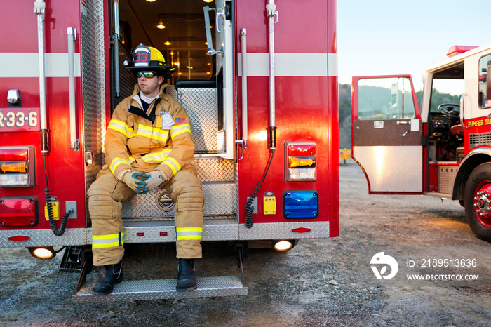 Firefighter sitting on back of fire engine