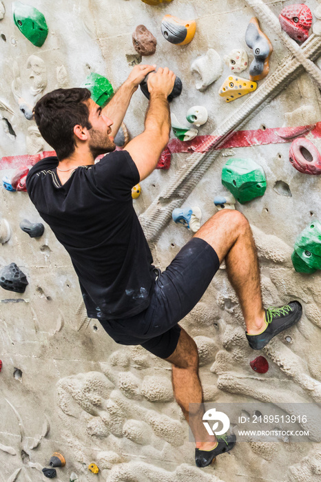 Man practicing rock climbing on artificial wall indoors. Active lifestyle and bouldering concept..