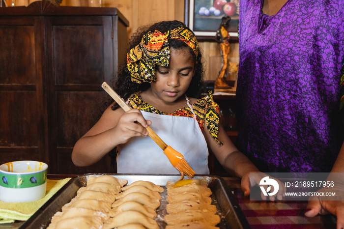 Horizontal de una niña afrocaribeña ayudando a su madre a preparar unos deliciosos bocadillos al est