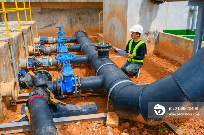 Manual worker turning big valve in industrial plant