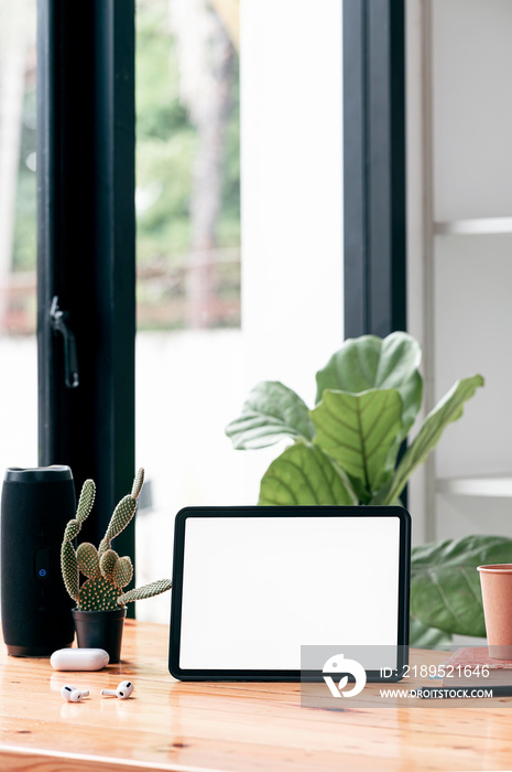 Mockup blank white screen tablet and gadget on wooden table in living room, vertical view.