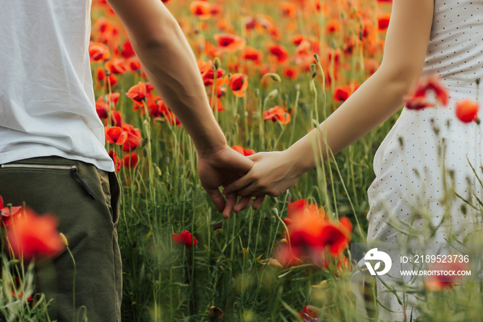 Close up outdoor portrait of couple holding hands in the red poppy field. Love - romantic couple hol