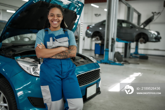 Keep your auto moving. Young african american woman, professional female mechanic smiling at camera,