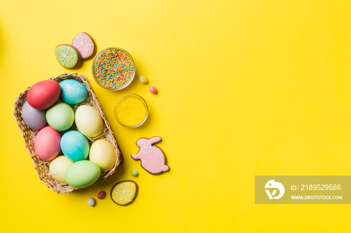 Colorful easter cookies in basket with Multi colors Easter eggs on colored background . Pastel color