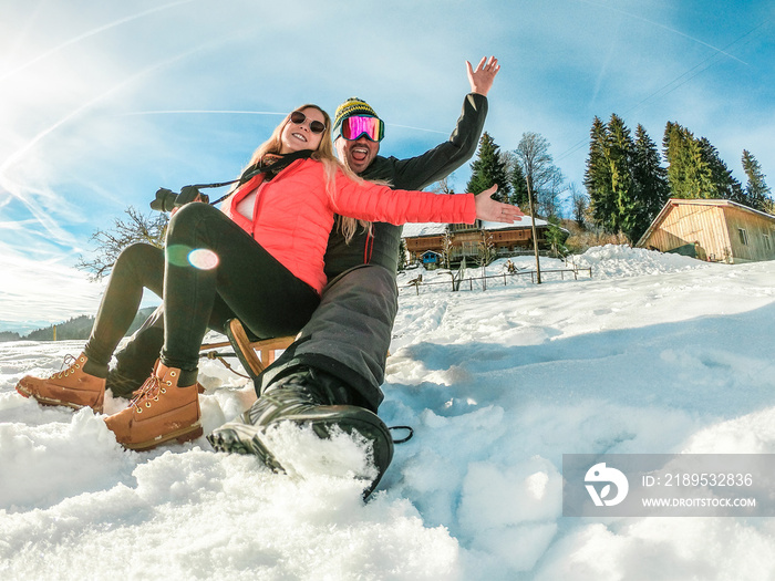快乐的疯狂夫妇在雪山上玩木制复古雪橇-年轻的有影响力的人