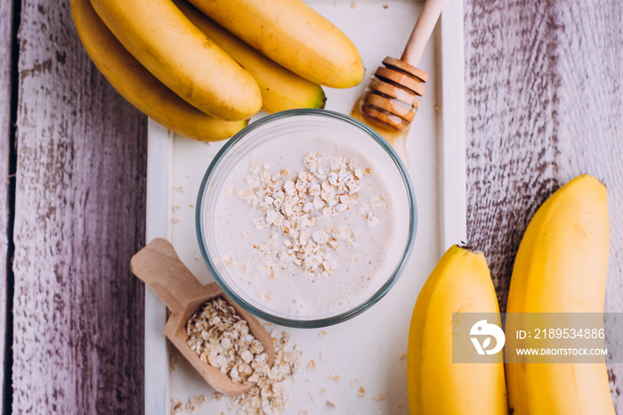 Delicious Healthy breakfast or snack. Banana smoothie with oat flakes, yogurt and honey in glass on 