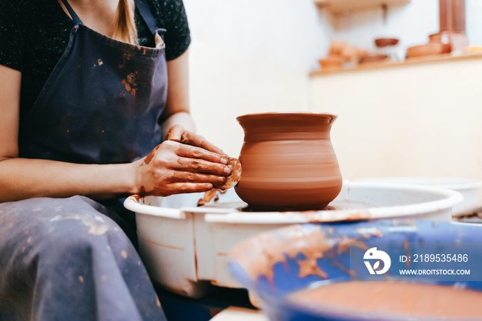 Woman potter molding clay dishes on a pottery wheel