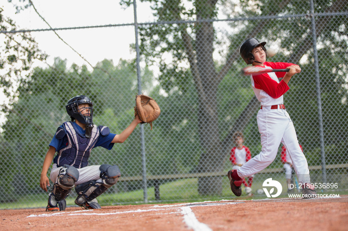 Young male baseball player swinging at baseball