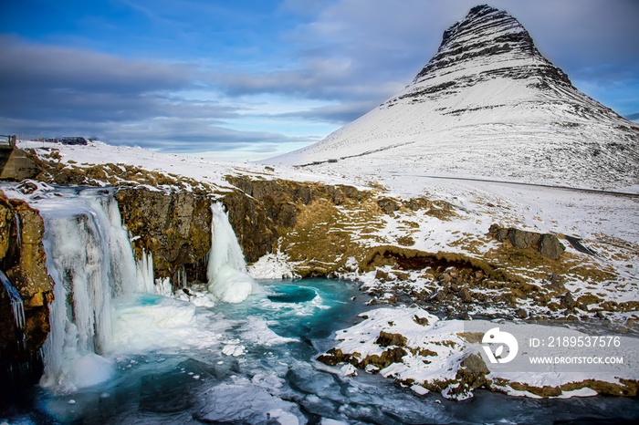Frozen waterfall with the mountain Kirkjufell in the Snæfellsnes peninsula in Iceland