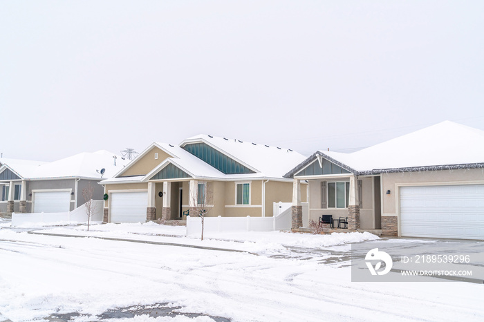 Front view of single storey family homes with attached garages against white sky