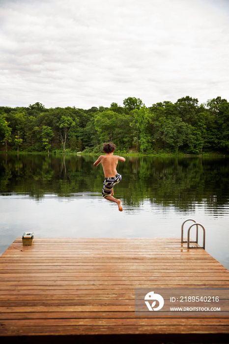 Rear view of boy jumping in lake