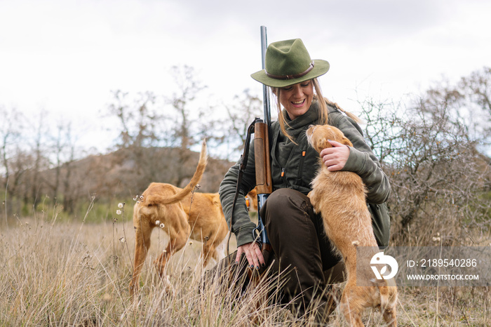 Hunter woman hugging her dogs.