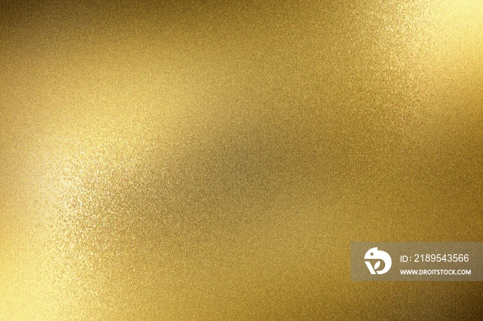 Light shining on rough gold metal panel, abstract texture background