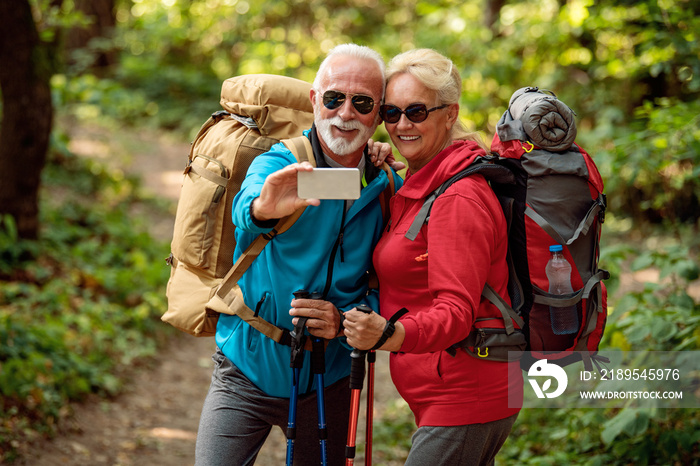 Happy senior couple of hikers in the forest.