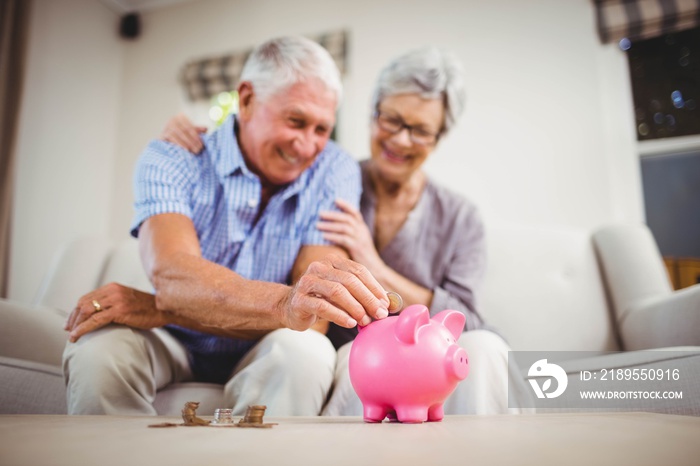 Senior man putting coins in piggy bank