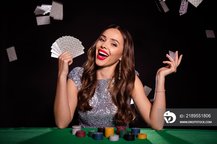 Photo of happy excited young woman fall cards deck sit table play poker winner isolated on black col