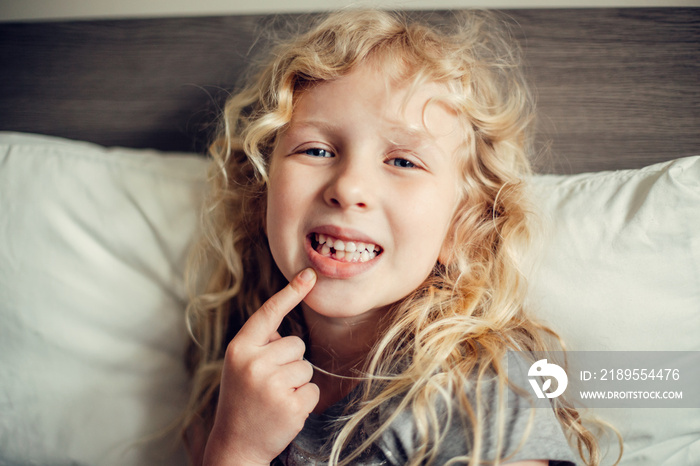 Cute Caucasian blonde girl showing her missing tooth in mouth. Proud child kid showing lost tooth an