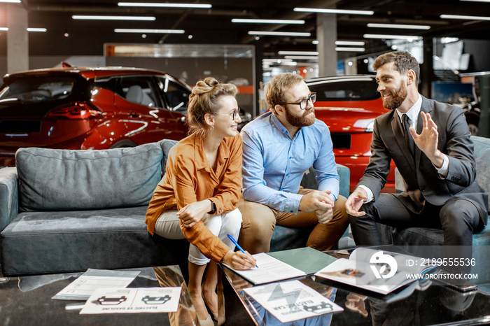 Young couple with saller on the couch at the car dealership