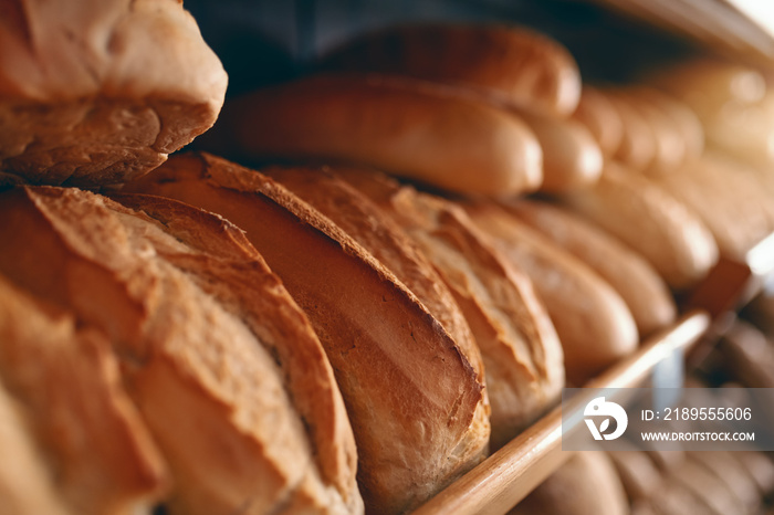 Close up of fresh delicious loafs of bread in row on shelves ready for sale. Bakery interior.