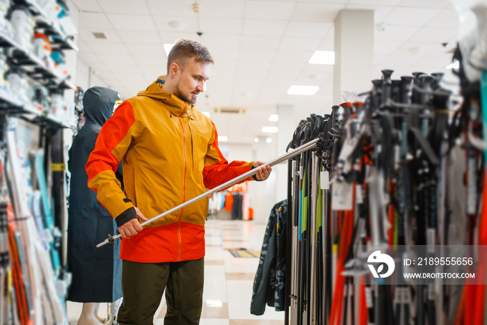 Man choosing ski poles, shopping in sports shop