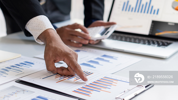 Male hand pointing to business graph document during conference room conversation. Laptop background