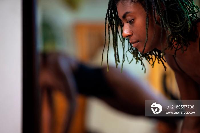 Black woman with dreadlocks spending time practicing yoga meditating and stretching