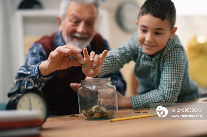 Grandpa and grandson saving money. Grandfather teaching grandchild how to save money.