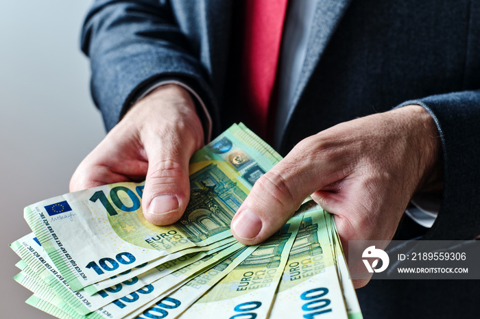 Businessman offering payment in new hundred euro banknotes