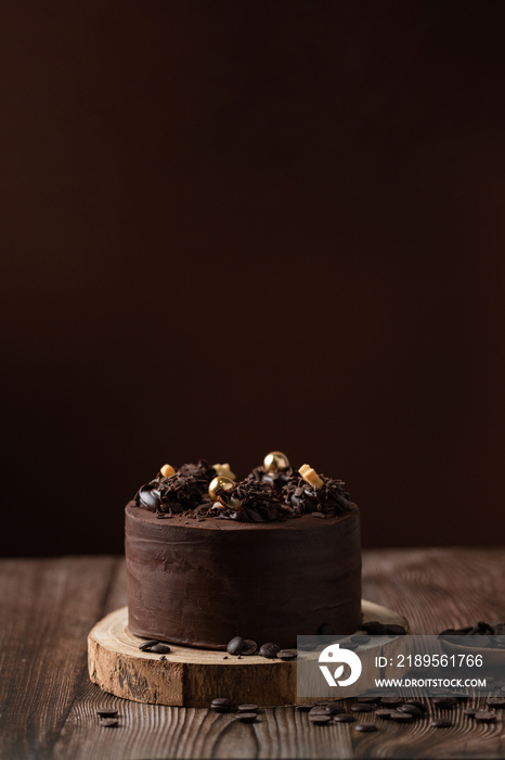 巧克力蛋糕的正视图，配有巧克力片、勺子和木桌。