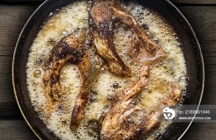 Fish in a frying pan. horizontal view from above. On the wood