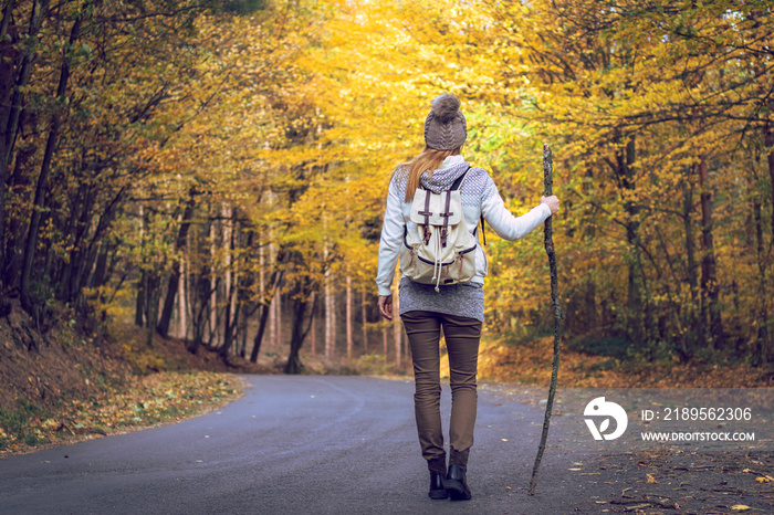 Woman hiking on road in autumn forest