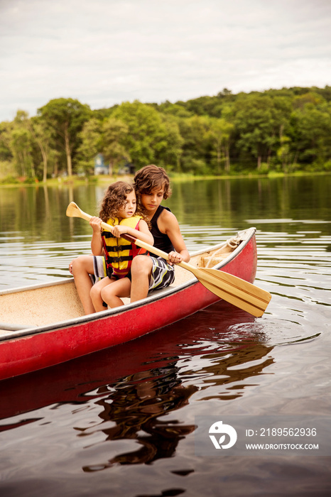 Siblings rowing boat in lake