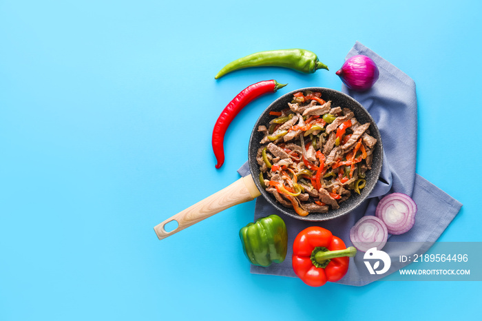 Frying pan with tasty Fajita and vegetables on color background